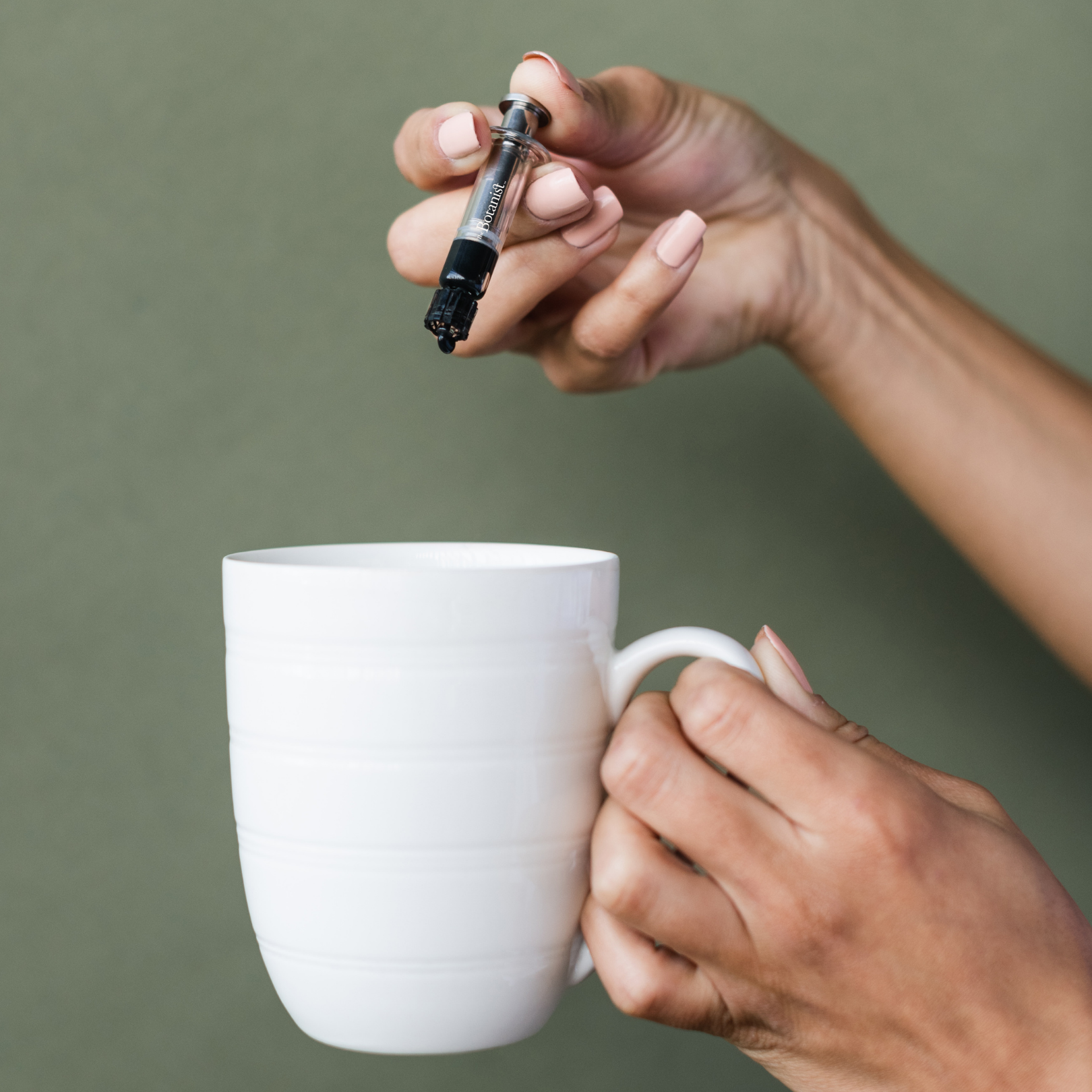 Hand holding RSO syringe and cup
